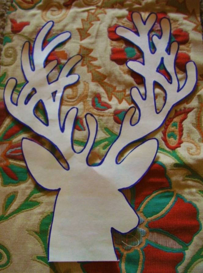 Deer face paper cutting placed on floral fabric.