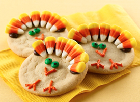 A cookie has decorations on top with candy corn and sprinkles.
