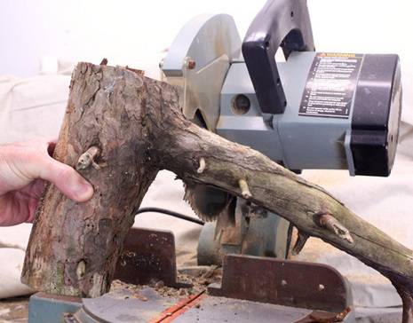 Man holding raw wooden piece to cut with cutter.