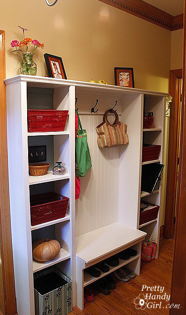 A white set of shelves holding boxes bins and hanging purses