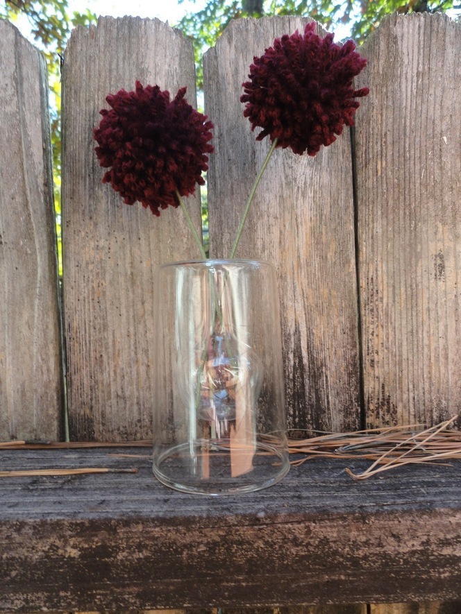 Maroon color yarn flowers on glass in the garden.