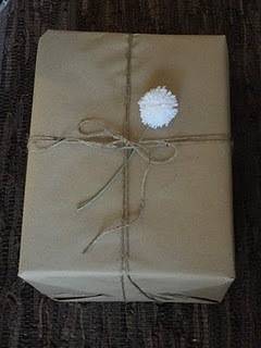 Gift box tied with tread and top up with white yarn pom pom.