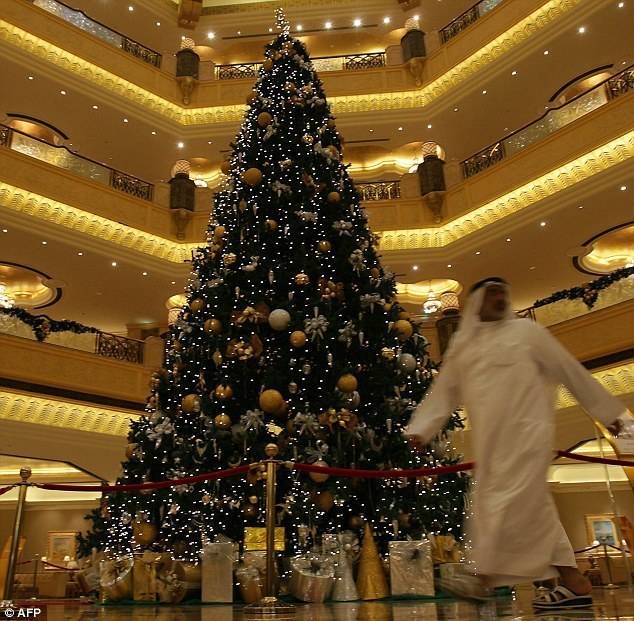 Opulent: A guest walks past the $11million Christmas tree in the Emirates Palace hotel atrium in Abu Dhabi