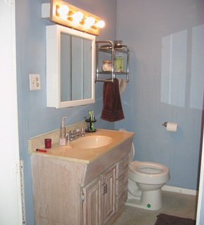 A bathroom with a view of a white sink, white toilet and a brown towel hanging.