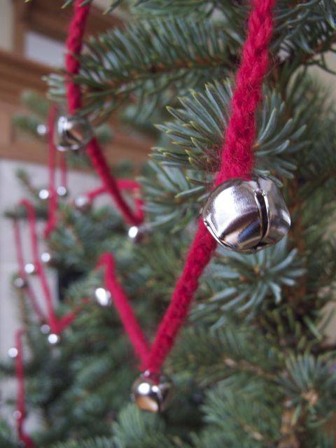 A jingle bell hung off a Christmas tree.