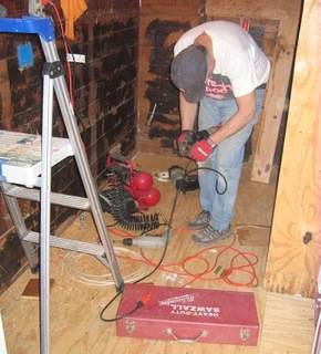 A man is using a tool in a small construction area.