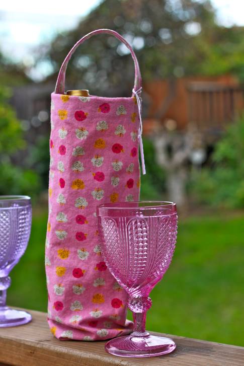 Wine bottle is placed in a pink color round shaped bag.