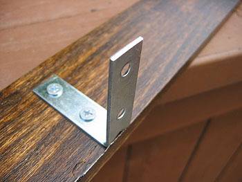 An L-shape metal clip attached to a wooden piece.