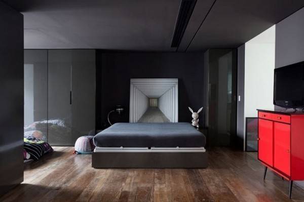 A modern minimalist bedroom with hardwood floors and a bright red cabinet.