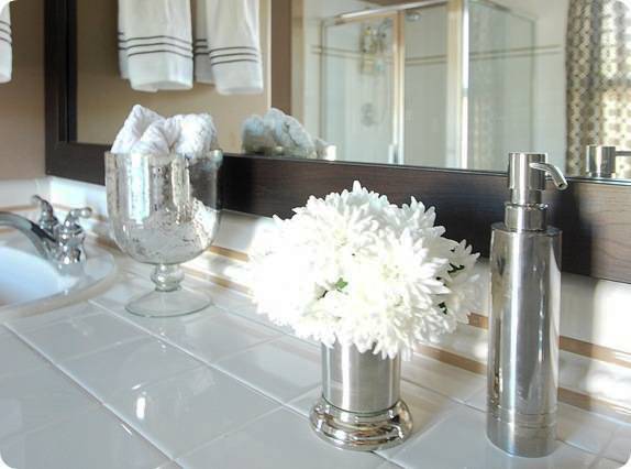 A glass, vase and steel soap dispenser lying near the washbasin.