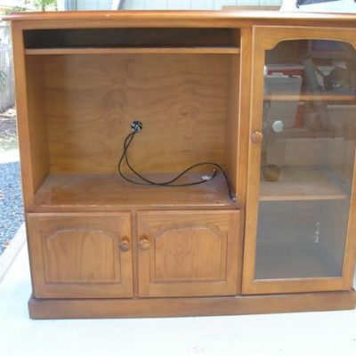 An old wooden TV stand cabinet with glass doors on side shelves