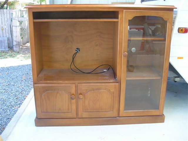 An old wooden TV stand cabinet with glass doors on side shelves