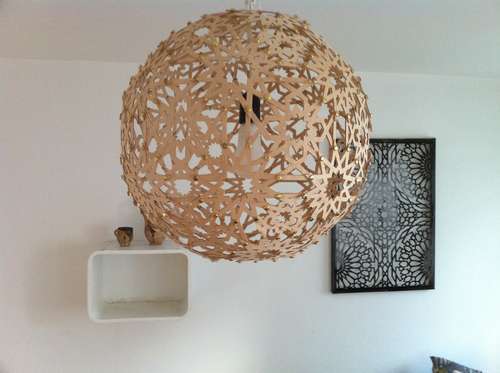 A large tan circular chandelier has flower like shapes on it