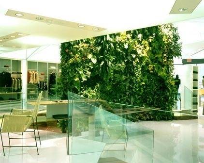 A patio area has a green plant wall and green furniture.