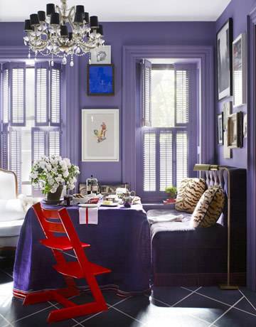 Dining table and chairs covered with purple color cloth with potted plants and dining plates in the purple color room.