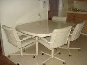 White color dining table with four rotating chairs.