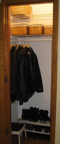 An open closet with many identical black jackets hanging from hangers on the left side.