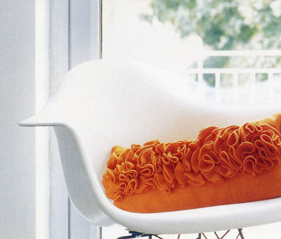 Orange pillow on the white chair.