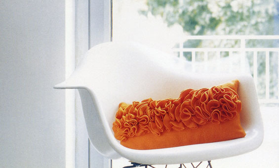 Orange pillow on the white chair.