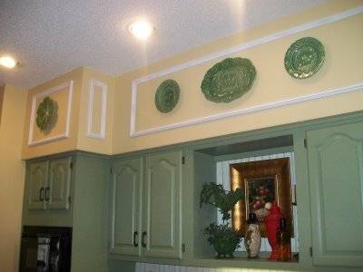 Green color kitchen cabinets and yellow walls with white roof.