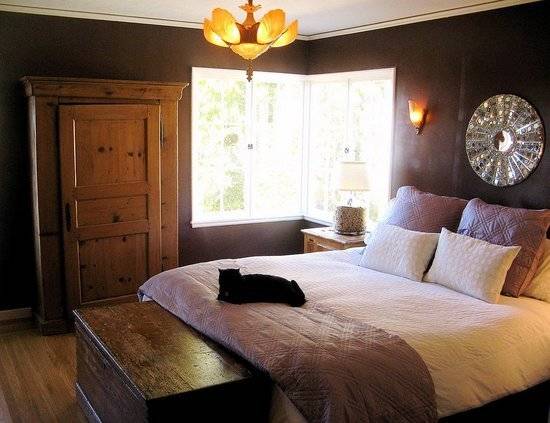 A bedroom having brown walls, wooden floor and a glowing chandelier hanging from the roof.