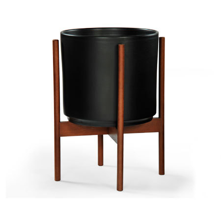 A Black cauldron planter upheld by wooden legs.