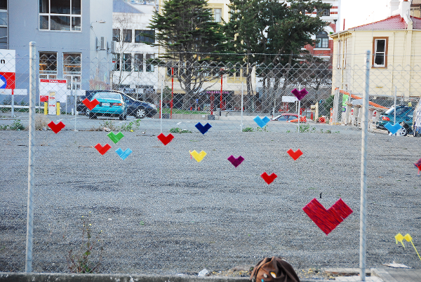 Colorful hearts are connected to a fence near a playground.