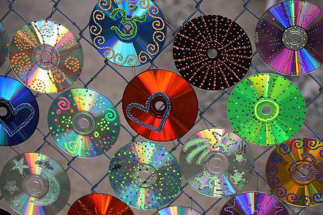 Several colorful CDs hang from a metal gate.