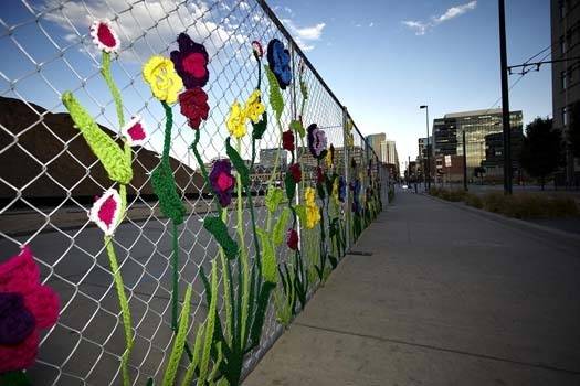 Designs with flowers decorate a chain link fence.