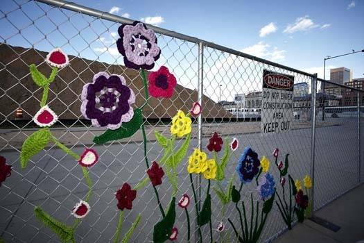 Colorful flowers are decorating a chain link fence.