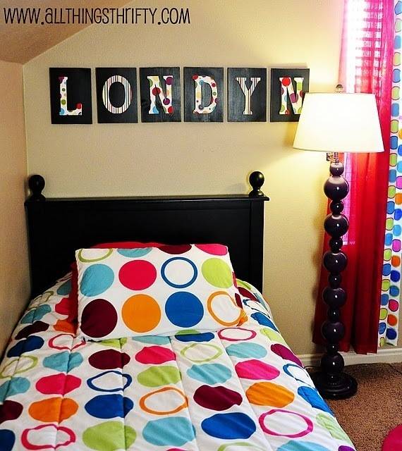 Bedroom with wooden bed with multicolored circle printed bed sheet and spherical base lamp aside.