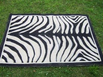 A zebra print rug lying on grass outdoors.