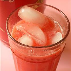 A pink tropical drink with ice cubes in it.