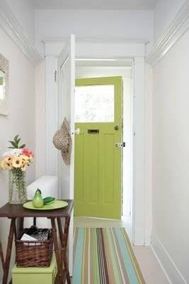 A green door at the end of a colorful floor mat.