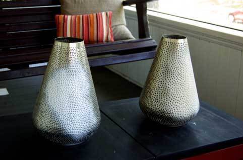 Two vases kept on the table near the wooden bench.