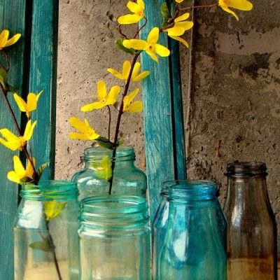 Blue color glass bottles with yellow color flowers stem inside.