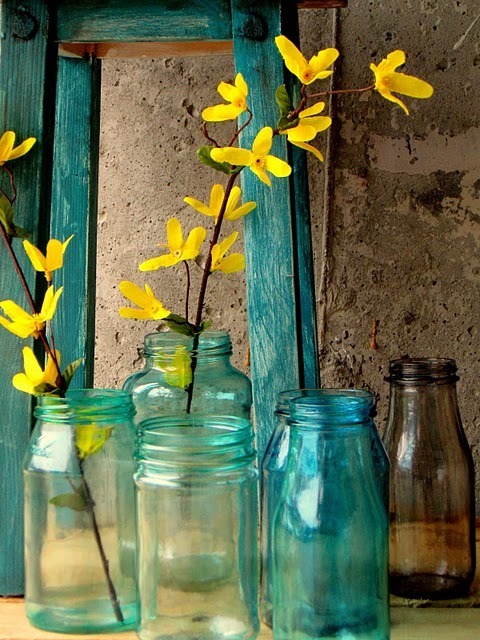 Blue color glass bottles with yellow color flowers stem inside.
