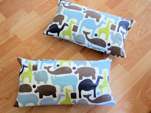 Two pillows covered with animal printed fabric on floor.