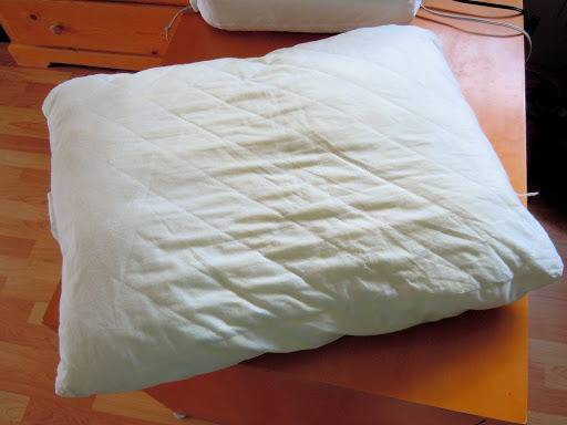 A bed pillow laying on a computer desk.