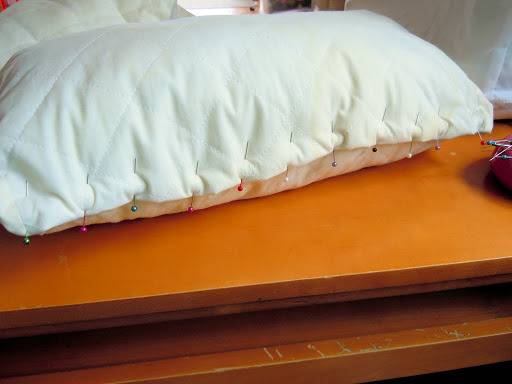 Colorful round headed pins pinned to a white pillow.