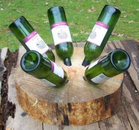 Five green wine bottles are upside down in a log of wood