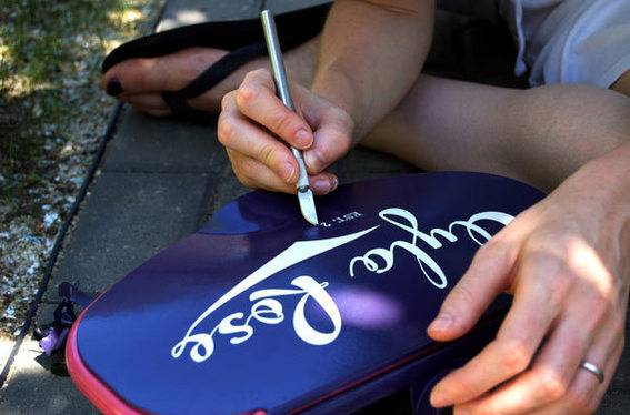 Alicia carefully peeling up the decal to reveal Ayla's logotype