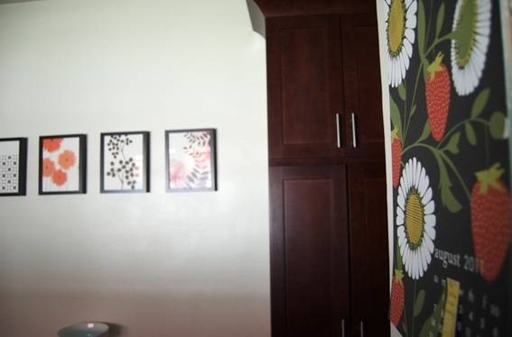 Four pictures of flowers on a wall with a cabinet on the right side.