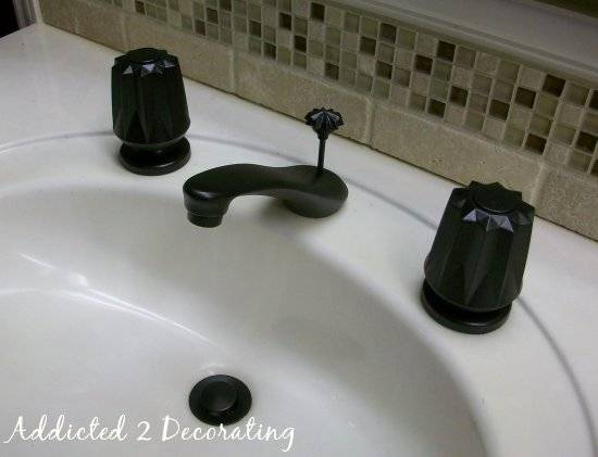 A white sink has black handles and faucet.
