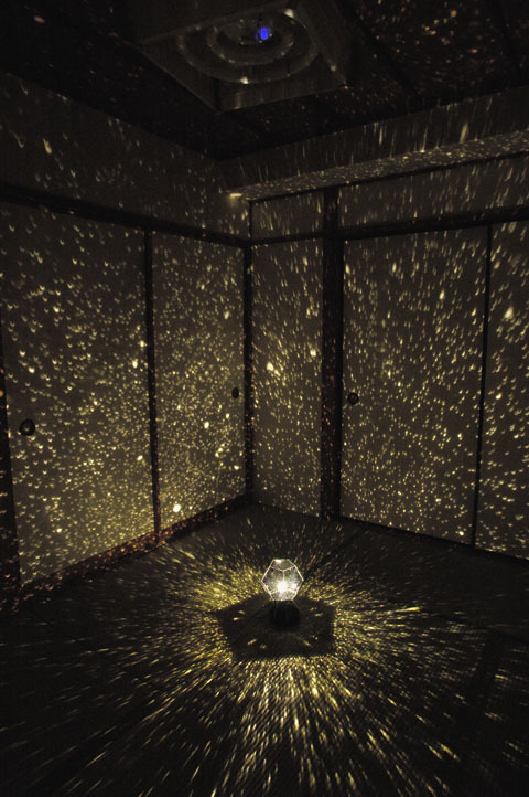 Room filled with sparkle lights coming from star projector at night.