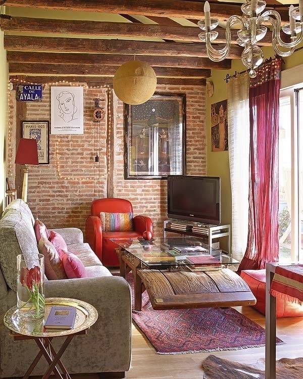 A living room has a brick back wall and exposed ceiling beams.