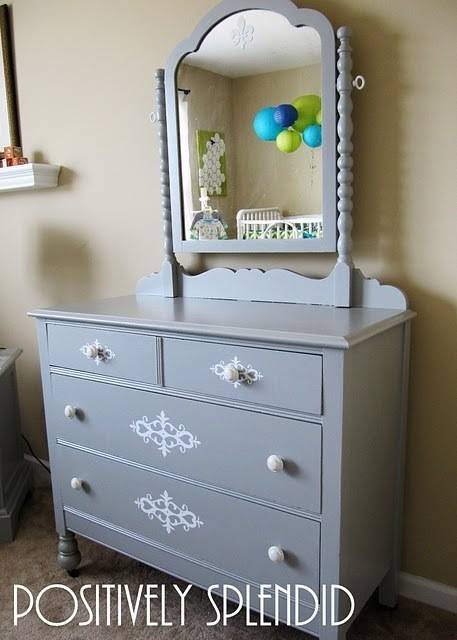 A grey dresser with a mirror on top.
