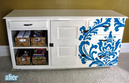 A white cabinet with blue designs painted on it.