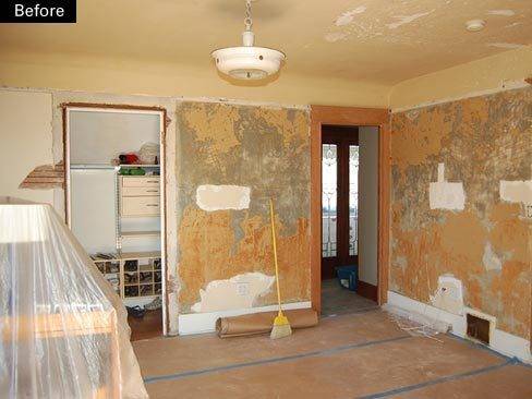 A room is being remodeled and has stripped walls and one piece of furniture covered in plastic.