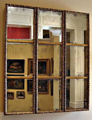 A window that shows several framed paintings outside of it.
